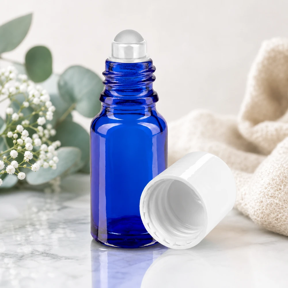 Butelka apteczna niebieska 10ml nakrętka roll-on biała Kobaltowo-niebieska szklana buteleczka apteczna typu roll-on o pojemności 10 ml z przezroczystą szklaną kulką na marmurowym podkładzie