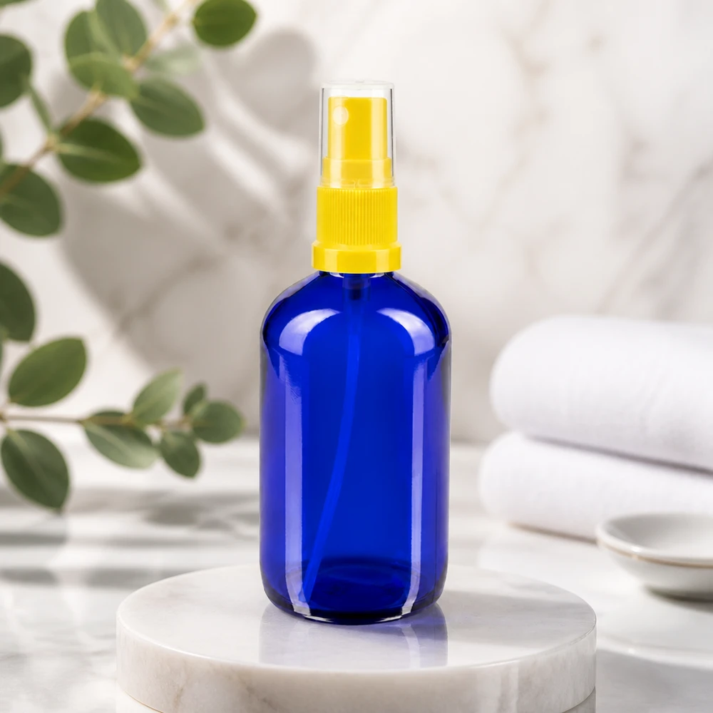 Butelka apteczna niebieska 100ml nasadka rozpylająca żółta Niebieska, okrągła butelka o pojemności 100 ml, wykonana ze szkła aptecznego, z żółtym rozpylaczem palcowym na marmurowym podstawku