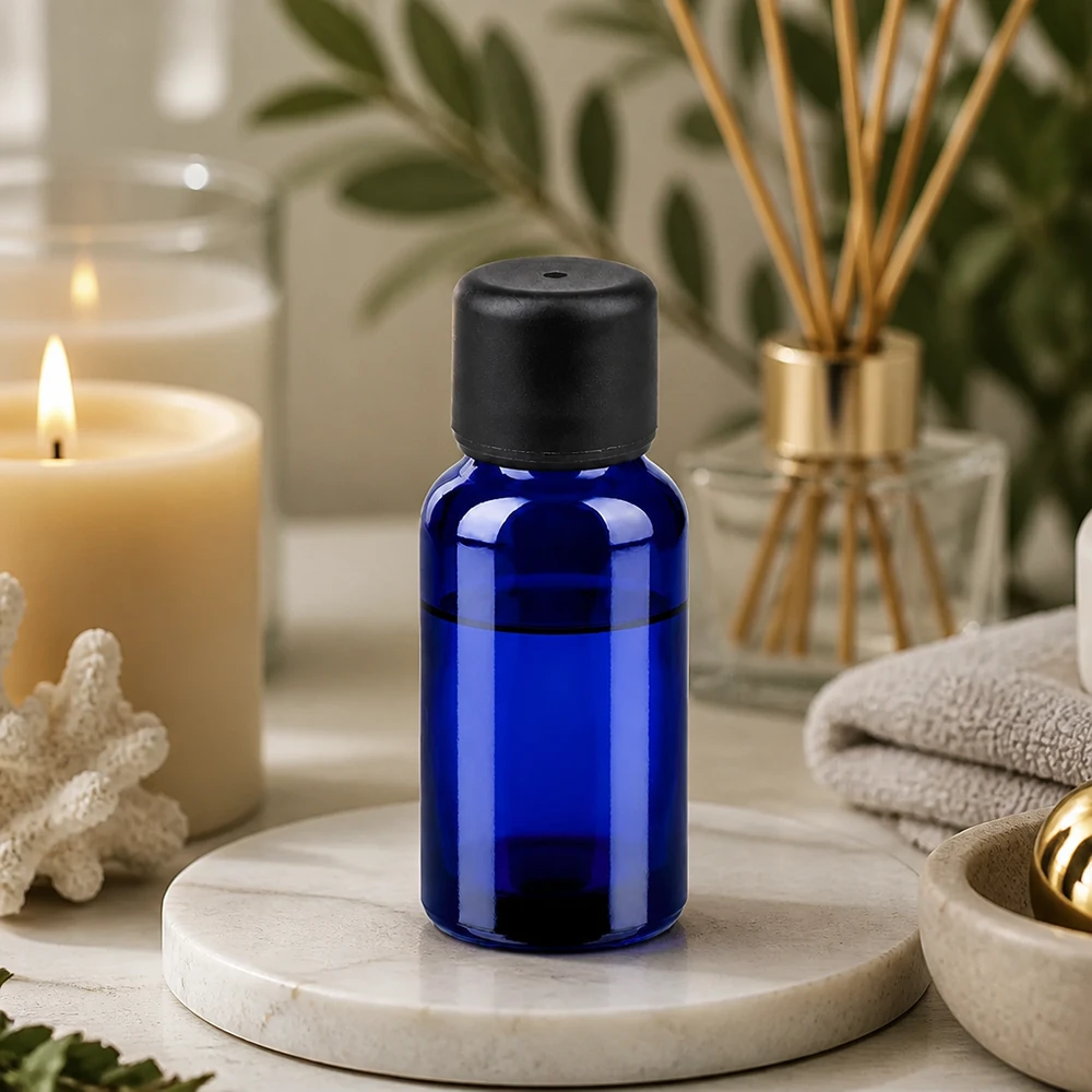 Elegancka szklana butelka w kolorze kobaltowego błękitu o pojemności 20 ml z matową czarną nakrętką do zastosowań w aromaterapii i spa.