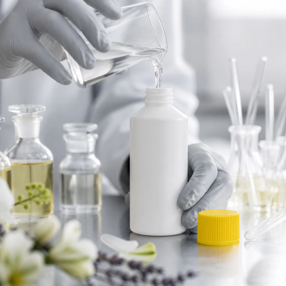 Napełnianie białej butelki z HDPE o pojemności 50 ml przezroczystym płynem z szklanego kubka w laboratorium