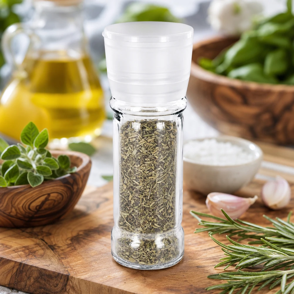 Słoik na sól/przyprawy 100 ml z młynkiem Vario, biały Słoik na przyprawy o pojemności 100 ml z białym młynkiem, wypełniony ziołami, obok rozmarynu i czosnku