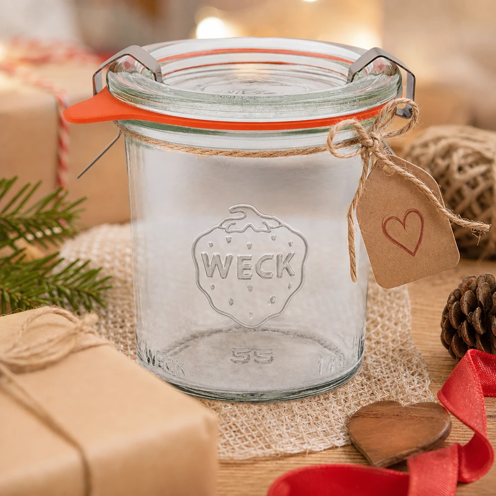 Kubki o pojemności 140 ml w komplecie WECK RR60 Kubki WECK 140ml RR60 jako pomysł na prezent ozdobione zawieszką w kształcie serca i sznurkiem jutowym na drewnianym stole z szyszkami sosnowymi