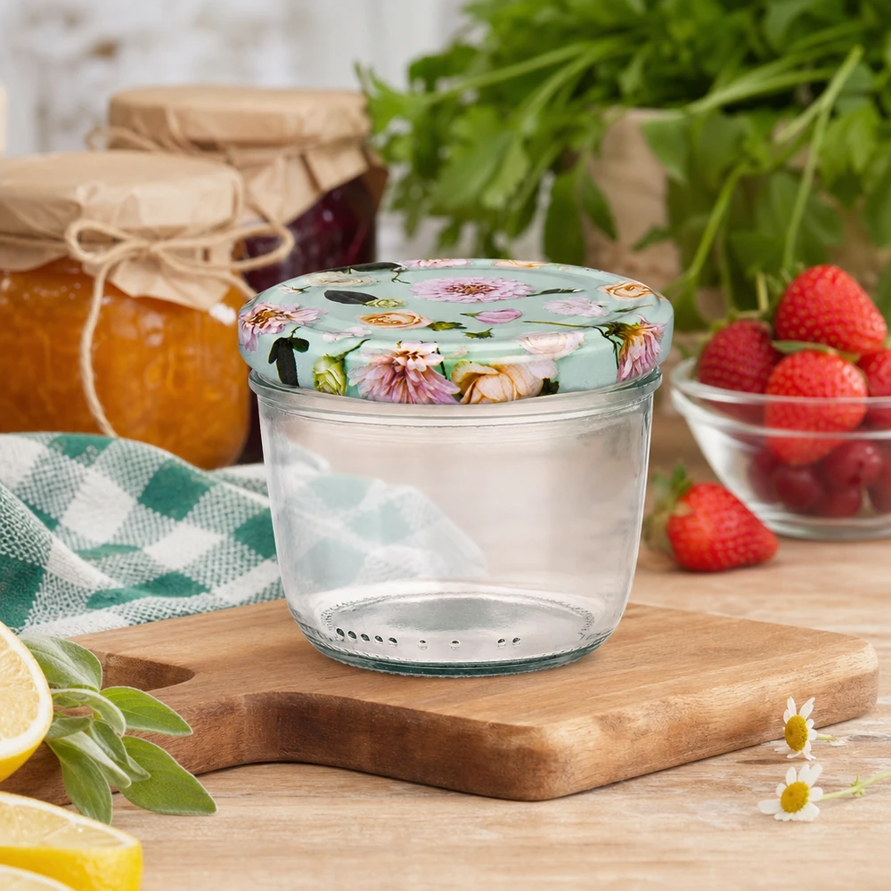 Szklanka z pokrywką 230 ml + pokrywka BasicSeal kwiat miętowa UN.. Kubki o pojemności 230 ml z kwiatową pokrywką BasicSeal na drewnianej desce, scena kuchenna z dżemem, truskawkami i ziołami