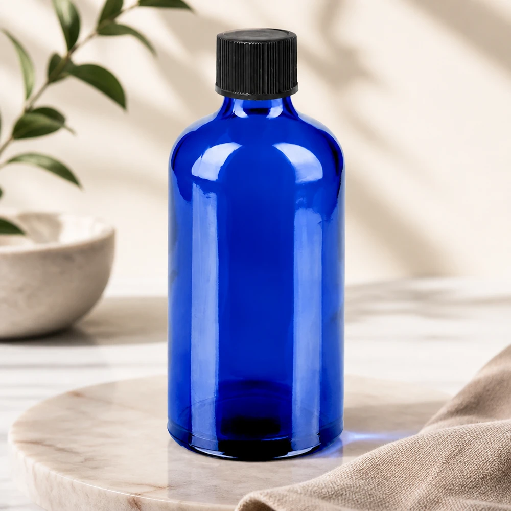 Kobaltowo-niebieska butelka z zakraplaczem o pojemności 100 ml i standardową czarną zakrętką do bezpiecznego przechowywania substancji wrażliwych na światło.