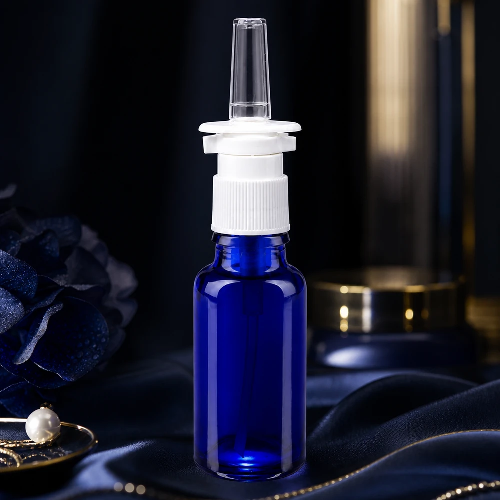 20 ml niebieska buteleczka na spray do nosa, wykonana ze szkła aptecznego, z białym mechanizmem pompującym na jedwabnej tkaninie