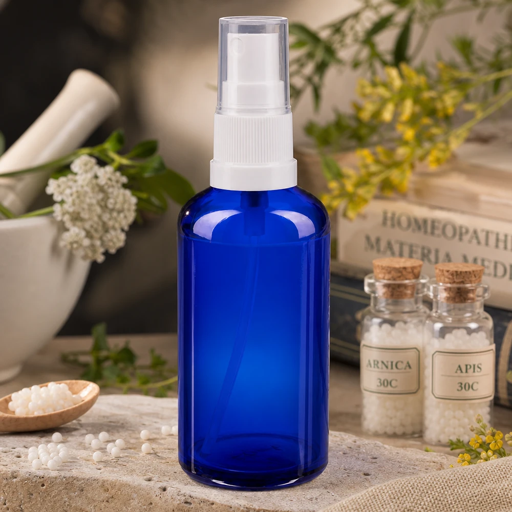 50 ml niebieska aptekarska szklana butelka z atomizerem i białą głowicą pompującą obok globulek homeopatycznych