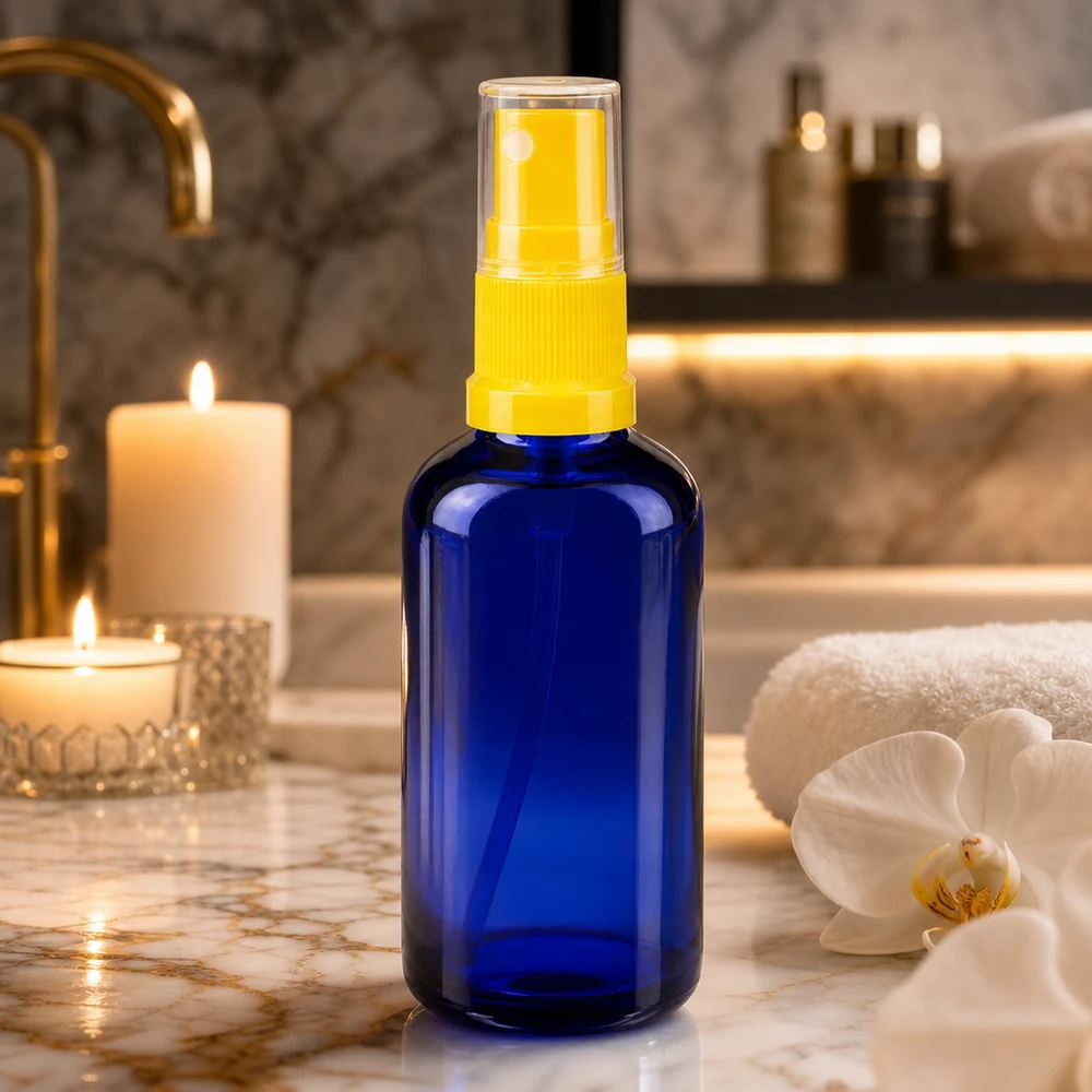 Niebieska butelka z atomizerem o pojemności 50 ml, wykonana ze szkła aptecznego, z przezroczystą głowicą rozpylającą na tle marmuru